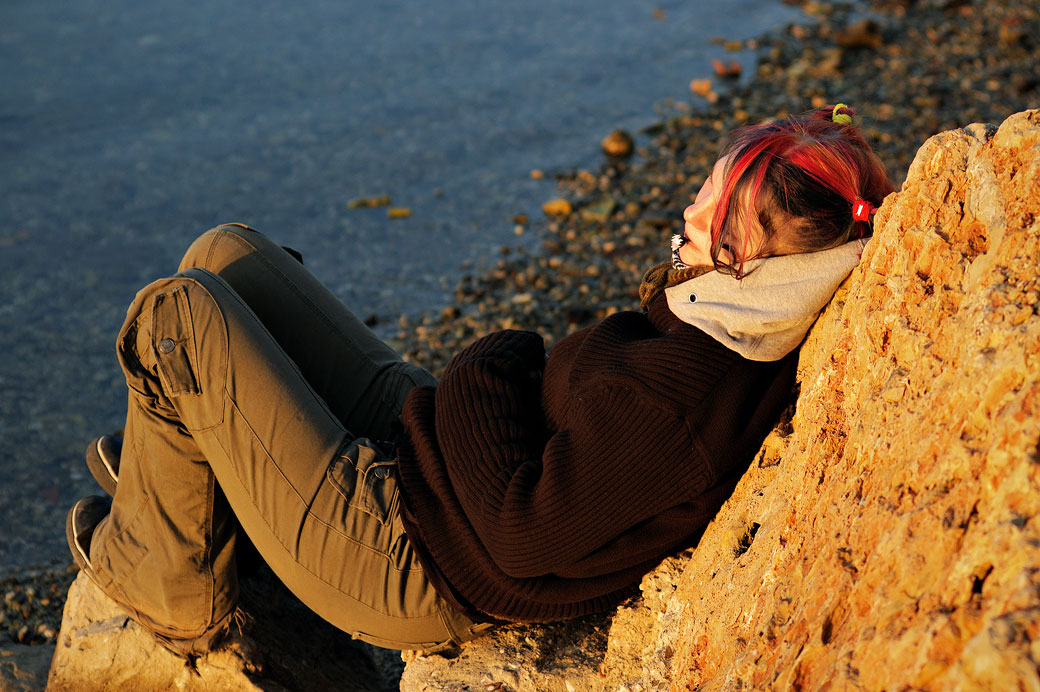 Jeune fille mélancolique au bord du rivage au coucher du soleil, France