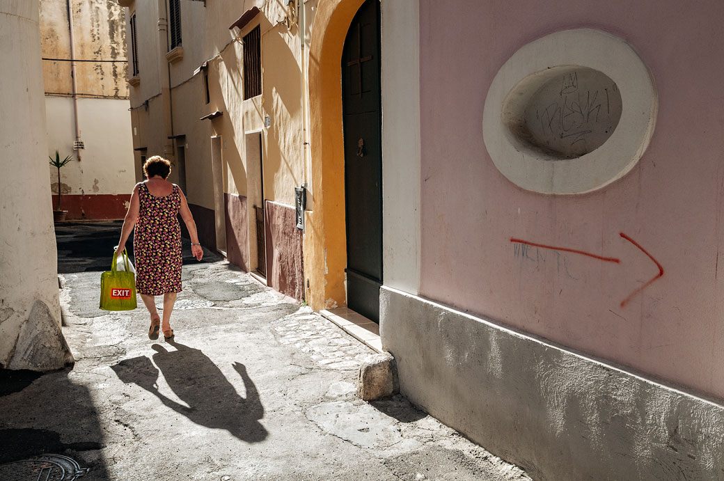 Femme suivie par son ombre dans une ruelle de Gallipoli, les Pouilles